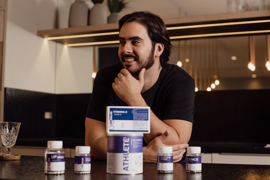 A man enjoying wellbeing surrounded by supplement bottles in a modern kitchen.