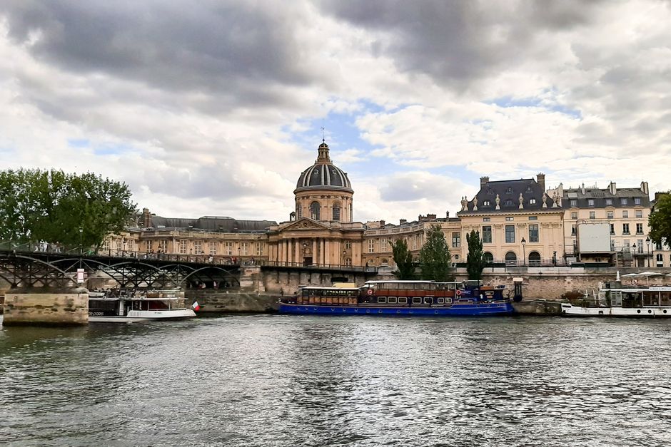 Scenic view of iconic Paris architecture along the Seine River on a cloudy day.