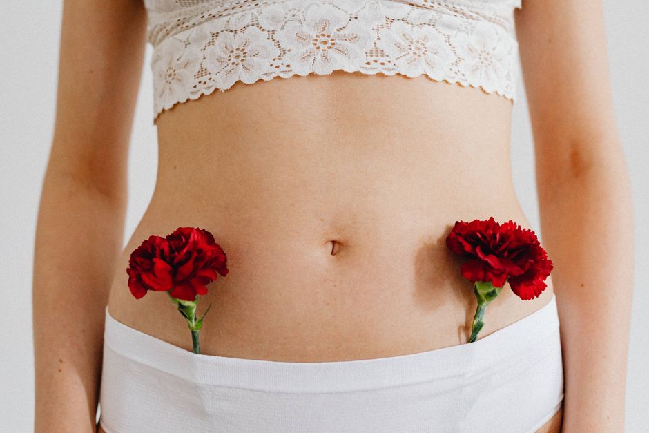 Conceptual close-up of red carnations placed on a human body in lace and underwear.