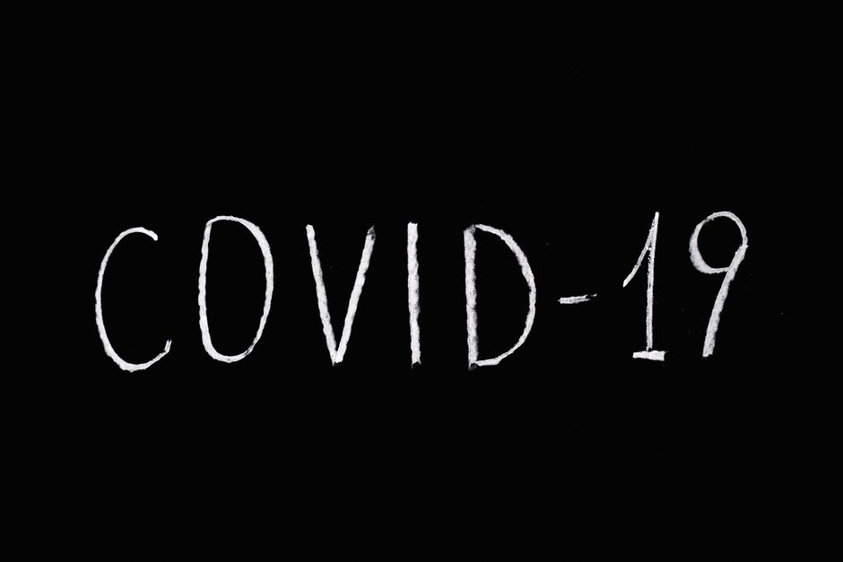 White chalked 'COVID-19' text on a blackboard background, emphasizing pandemic theme.