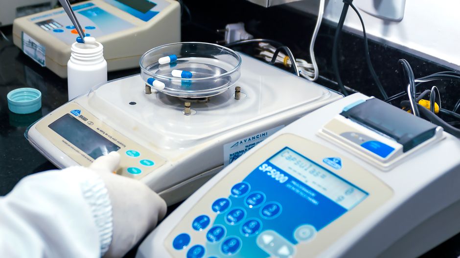 Close-up of laboratory equipment with capsules, capturing pharmaceutical analysis.
